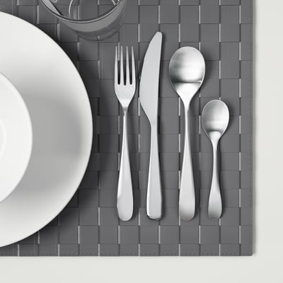 Silverware set on grey placemat: fork, knife, large and small spoons.