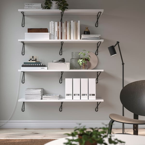Minimalist wall-mounted shelves with black brackets, holding books, decor & plants.