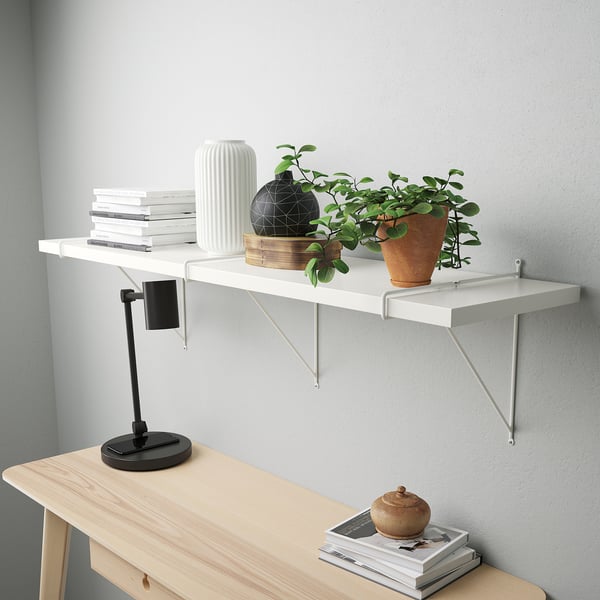 Modern wooden desk setup with shelf, books, vase, decor, plant, lamp and magazines.