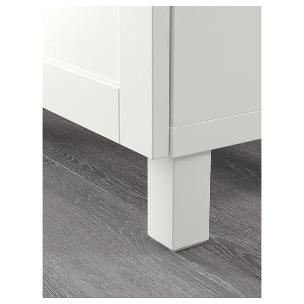 Modern white sideboard with sleek white legs on grey wooden floor.