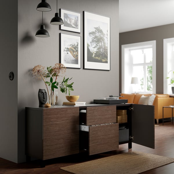 Modern wooden sideboard with adjustable shelves, drawers, and soft-close. Decorated with art, lights, and plants in a bright living room.