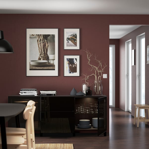 Modern dining room with maroon walls, black BESTÅ sideboard, decor, and natural light.
