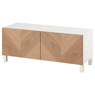 A white BESTÅ tv unit with wooden doors. It two doors with a chevron pattern and adjustable shelves.