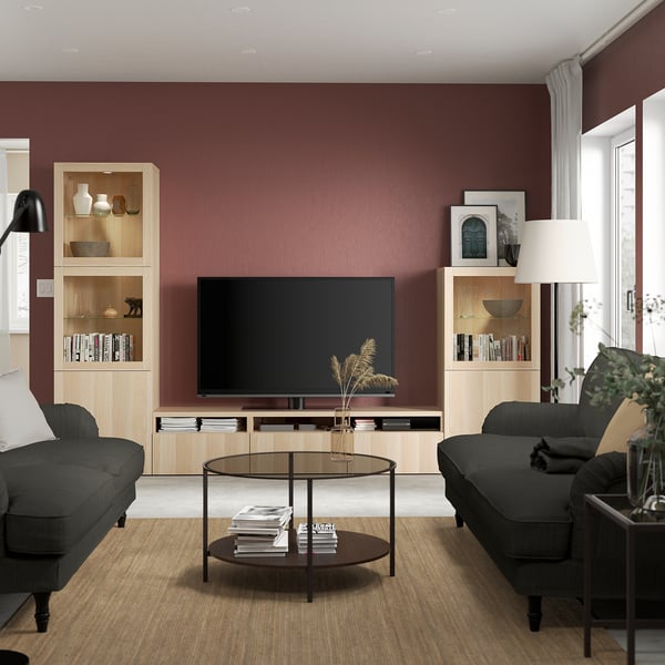 Modern living room with tv, bookshelves, sofas, coffee table, lamp, and window.