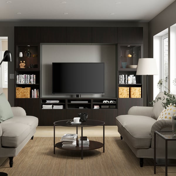 Modern living room with BESTÅ tv unit, grey sofas, centred tv, books, decor, and black coffee table with magazines.