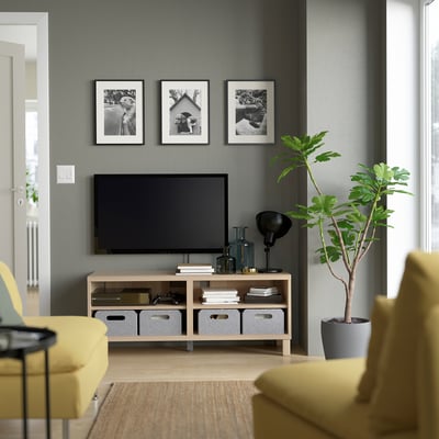 Living room with BESTÅ tv bench, chairs, plant, & photos.