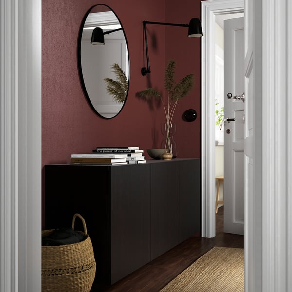 Black BESTÅ sideboard, books, plants, red walls.