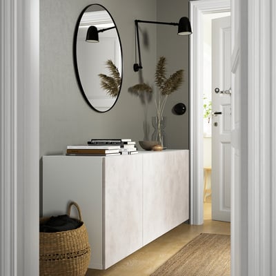 Minimalist entryway: BESTÅ cabinet, mirror, lamps, basket, bright room.