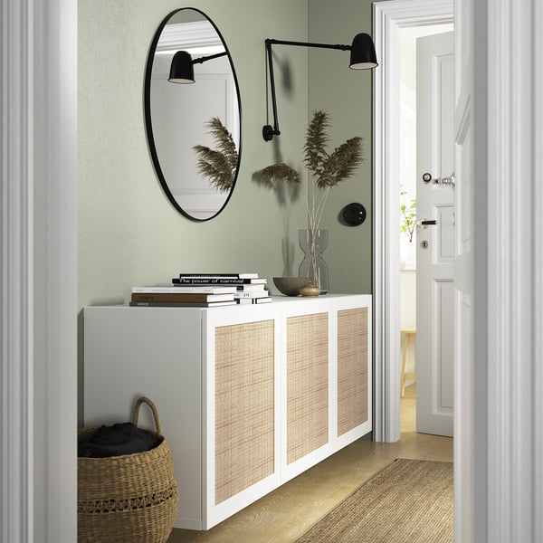 A modern hallway with a BESTÅ white sideboard, mirror, and sconces. Includes woven basket and wooden floor.