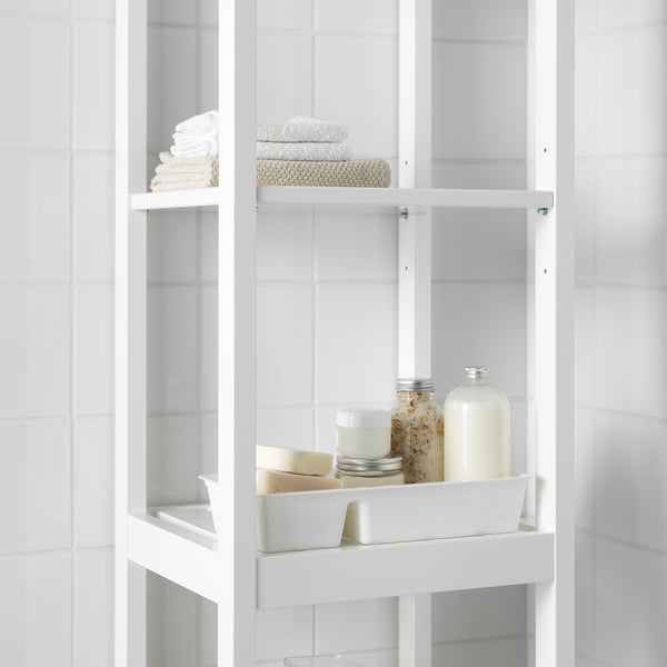 White shelf unit with a tray holding toiletries and folded towels.