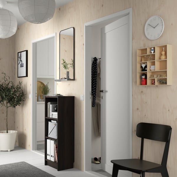Modern hallway with dark BILLY bookcase, open door, chair, clock, mirror, plant.