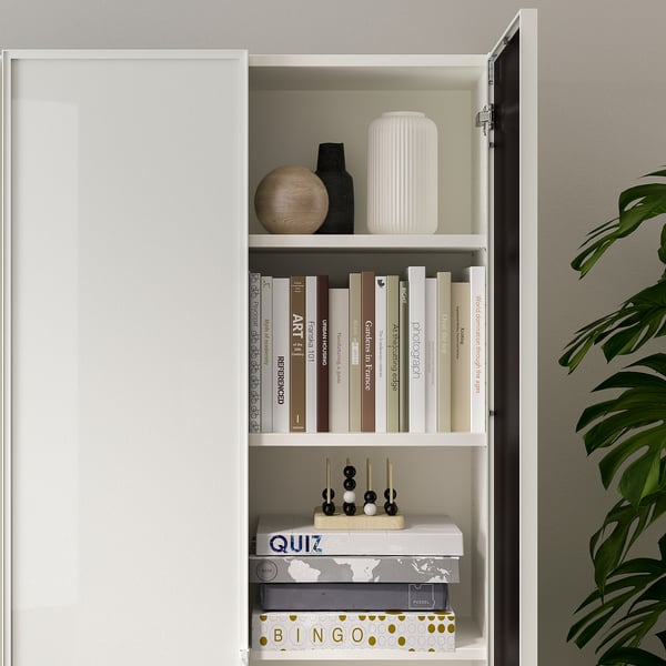 Closed bookcase with glass door displaying books, decorative items, and board games.