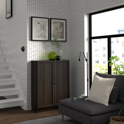A modern living room with a BILLY bookcase, decorative vase, grey sofa, and black floor lamp near a large window.