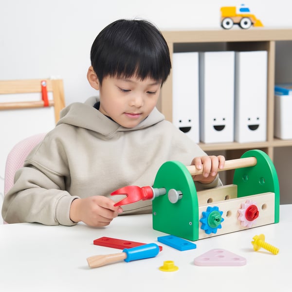 Young boy playing with BLOMFLUGA toolbox, hammer, and wrench, developing motor skills and creativity.