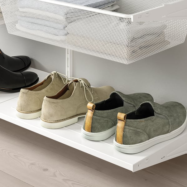 Wall-mounted shoe rack with mesh basket, storing various footwear.