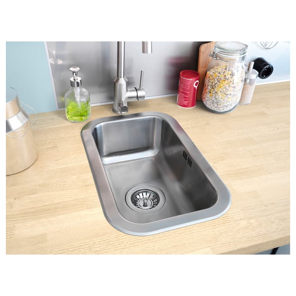 Stainless steel sink on wooden countertop with tap, soap dispenser, and food jars.