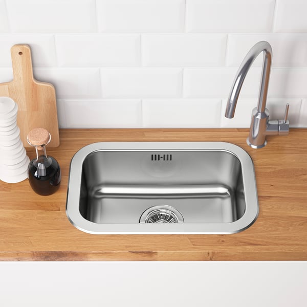 Stainless steel kitchen sink with modern tap, set in wooden countertop.