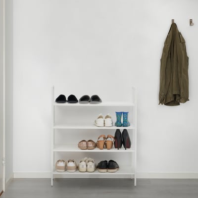 White, 3-tiered BOJTEN shoe rack, holding 16 pairs, against a wall with a hanging jacket.