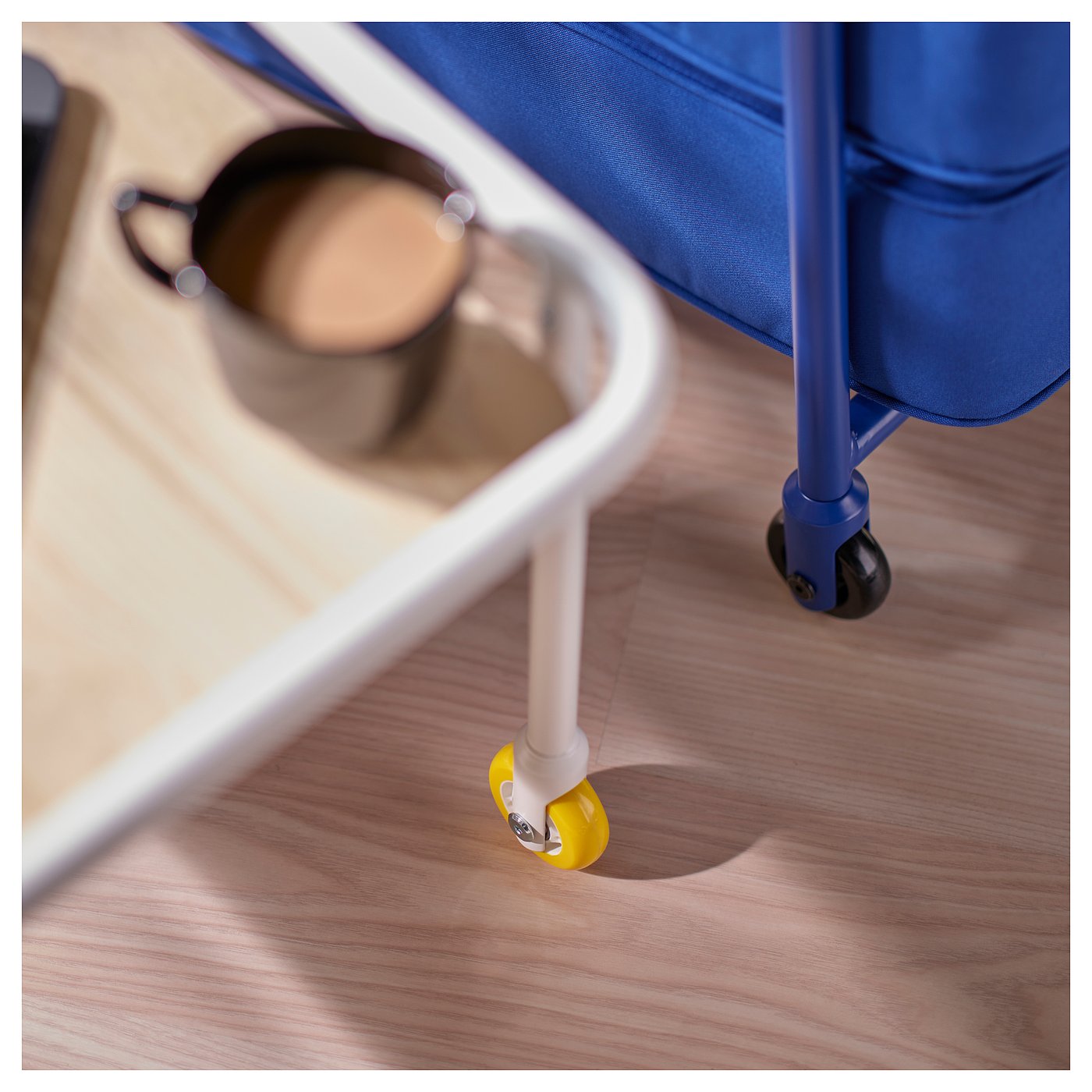 Close-up of mobile gaming side table. Vibrant blue fabric, sturdy wheels, and high edge for stability.