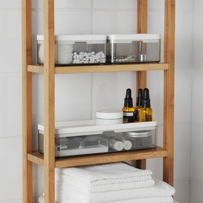 Wooden bathroom shelf with transparent storage bins and neatly folded towels.