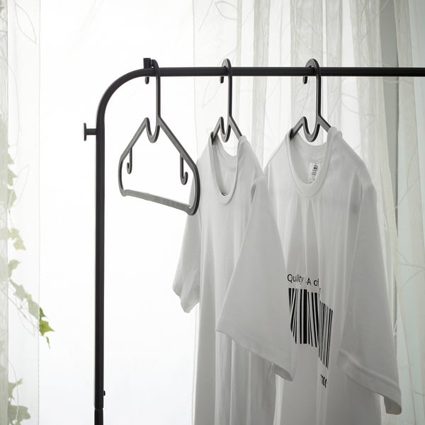 Three white t-shirts hang on a clothes rack, demonstrating organised storage.