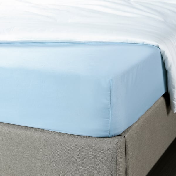 Light blue fitted sheet on grey bed, showcasing elastic edges for secure fit.