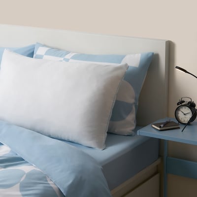 Blue BRUKSVARA pillow on bed, large, recycled microfiber & polyester filling.