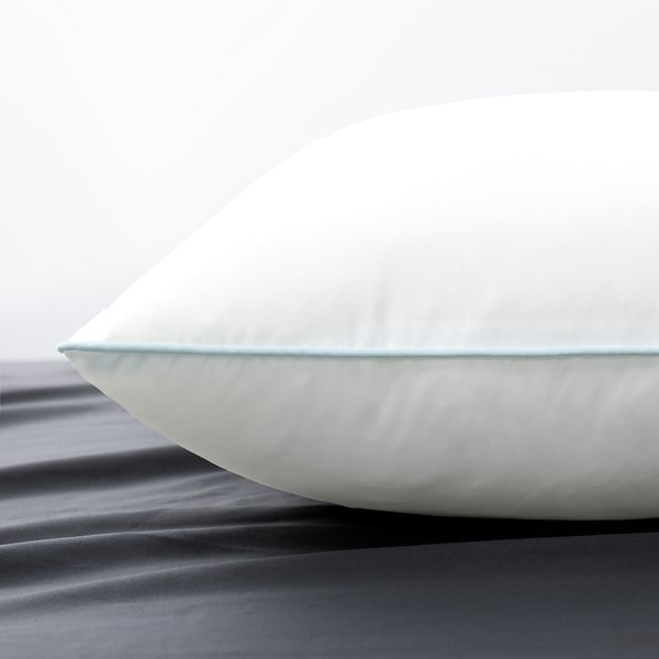 Close-up of a soft, white pillow with a smooth microfiber cover on a dark surface.