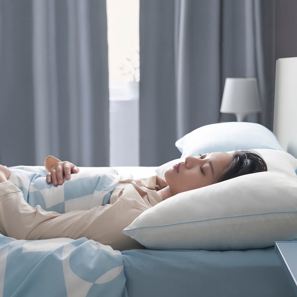 A person sleeps peacefully on a soft, machine-washable pillow with a brushed microfibre surface, ideal for stomach sleepers.
