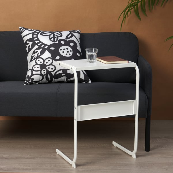 Small white side table on couch, holds glass and notebook.
