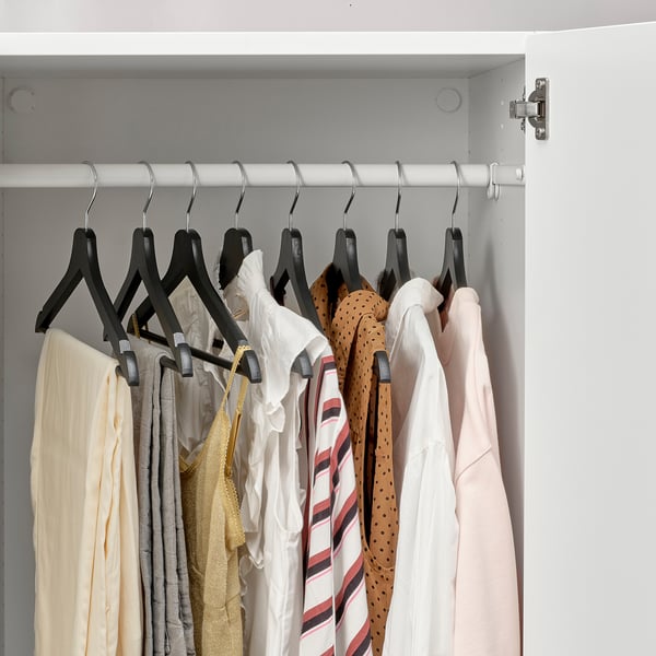 Closet with hangers holding various clothes, including a white and red striped shirt, showcasing an organised and neat wardrobe.