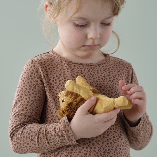 A young child holding a small plush lion toy, which is soft and huggable.