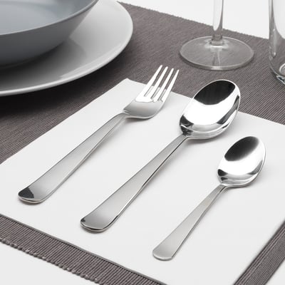 Polished metallic fork, spoon, and teaspoon neatly arranged on a white napkin, part of DRAGON cutlery set, suitable for elegant place settings.