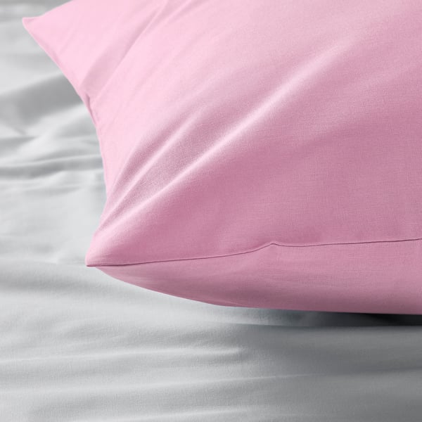 A close-up of a plush, pink pillowcase on a bed, showcasing its smooth, soft fabric.