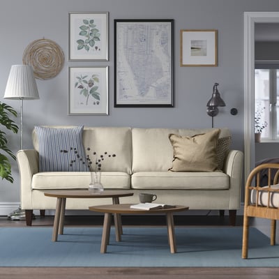 Beige 3-seat EKHOLMA sofa, removable covers, blue wall art, wooden coffee table, wicker chair, mid-century modern.