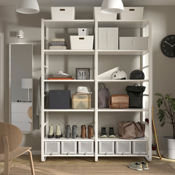 White ELVARLI storage unit with shelves and hooks holding various items, including bags, boots, helmets, and boxes; fixed to a wall.