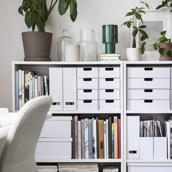 Organised home office featuring white FJÄDERHARV magazine files, blending neatly with books and potted plants on shelves.