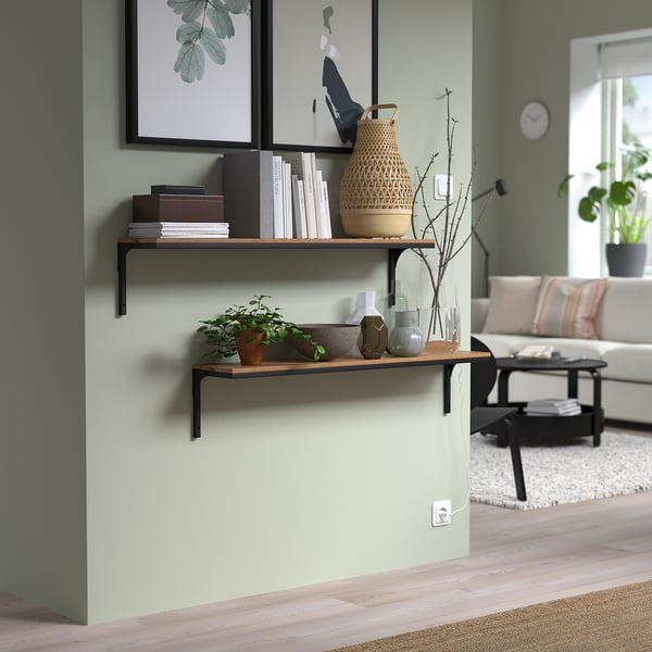 Modern living room with FJÄLLBO shelf, books, vases, and plants in muted green tones.