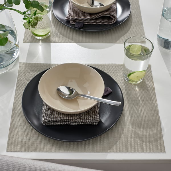 Table setting with FLYGFISK place mats, bowls, spoons, glasses, and greenery.