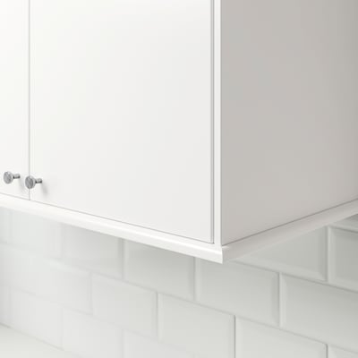 White kitchen cabinet trim, two silver knobs visible, mounted on white subway tiled wall.