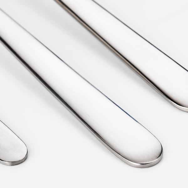 Polished stainless steel cutlery: forks, spoons, neatly arranged. Shiny, modern design.
