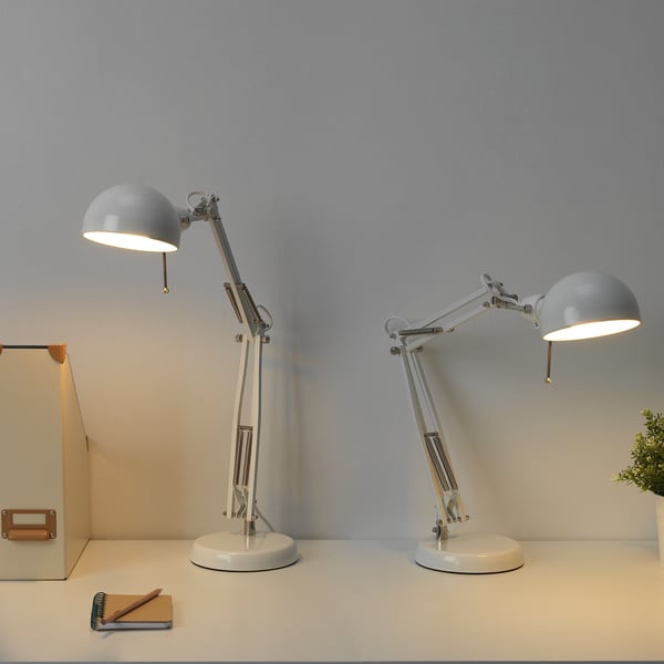 Two adjustable FORSÅ lamps on desk near books