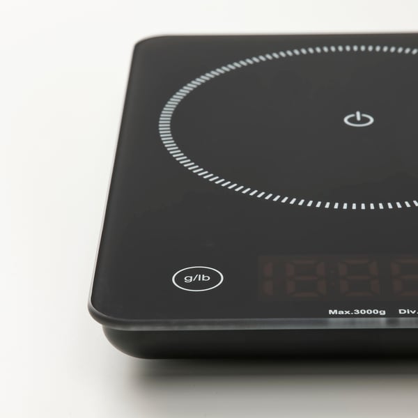 Black digital scale with glass surface, featuring circular light display and power button, resting on a white background.