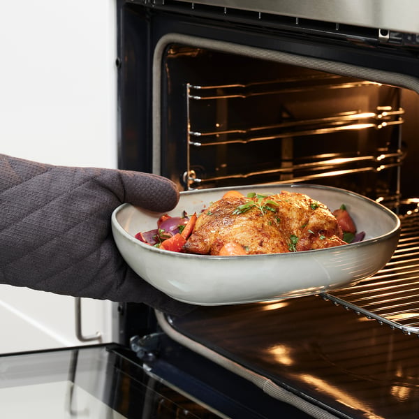 Person removing dish with roasted chicken and vegetables from oven.