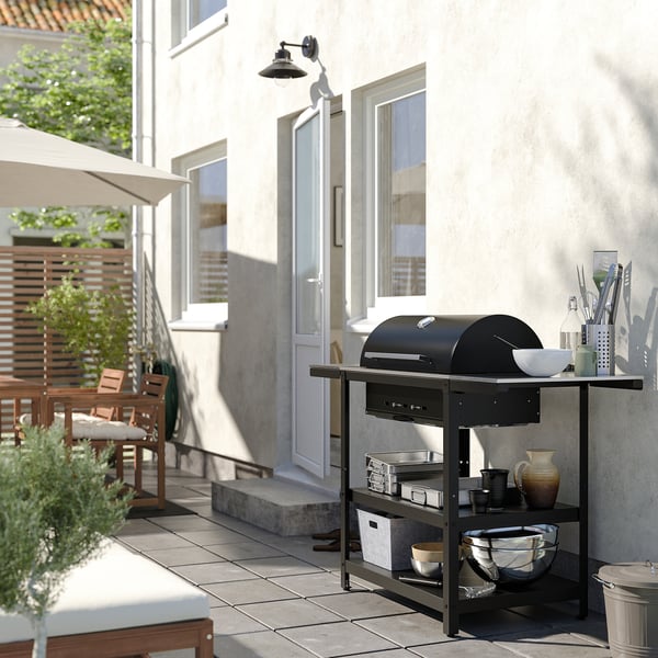 Charcoal grill on patio with table and umbrella.