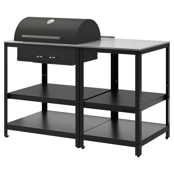 An all-black GRILLSKÄR charcoal grill on a metal stand with three shelves. The stand and grill are modern and sleek, designed for outdoor use.