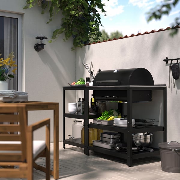 Black GRILLSKÄR grill set-up outdoors with accessories on shelves, perfect for patio.