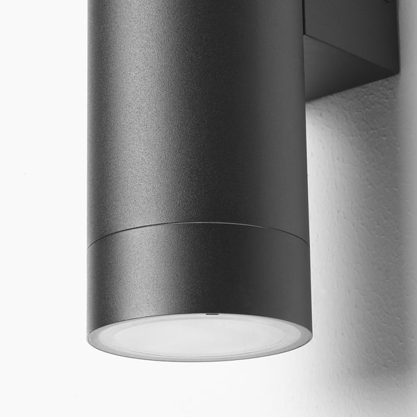 Modern outdoor wall lamp with matte black finish and sleek design, featuring two light sources casting a warm glow.