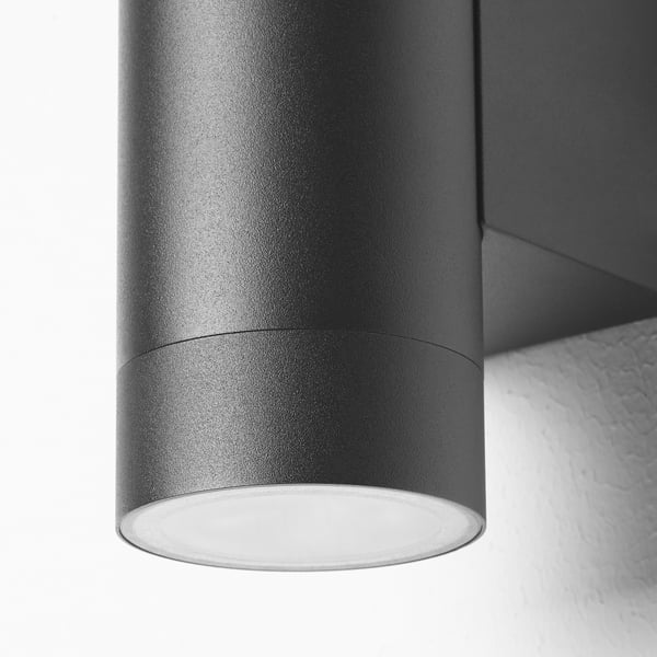 Black cylindrical outdoor wall lamp, part of modern decor, close-up of sleek design.