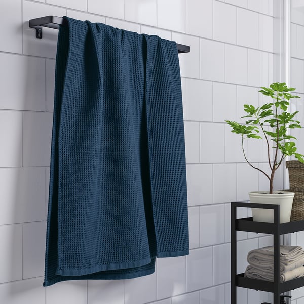 Blue towel on rack with plant and folded towels.